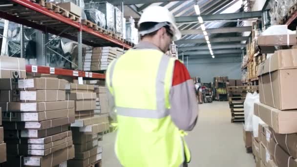 El trabajador del almacén cuenta y escribe con una pluma — Vídeo de stock