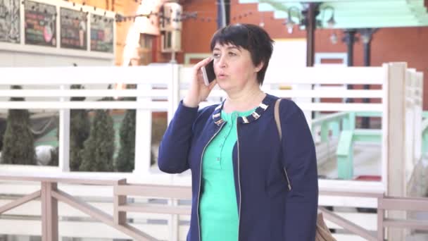 Женщина старше 40 лет разговаривает по телефону городской пейзаж — стоковое видео