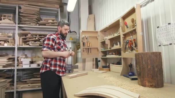 Man carpenter in a shirt with a beard uses tools in the workshop — Stock Video