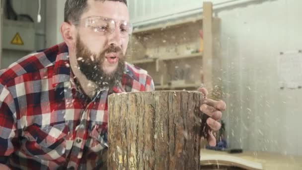 Carpenter muž v košili s bradkou fouká hoblin v dílně — Stock video