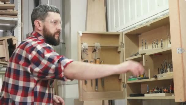 Muž tesař v košili s použitím vousy, které nástroje v dílně zblízka — Stock video