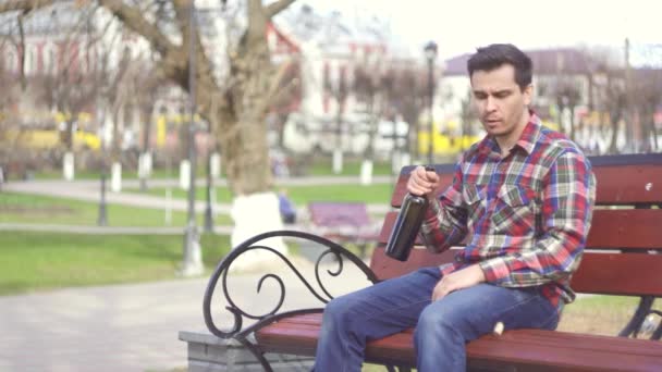 Hombre triste con ramo de flores y una botella de vino en el parque — Vídeos de Stock