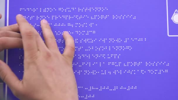 Ruce, slepý muž v košili číst Braillovo písmo na znamení budovy — Stock video