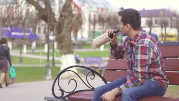 Homem triste com uma garrafa de vinho no parque — Vídeo de Stock