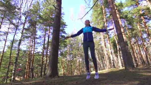 Спортивна дівчина розігрівається в сонячному лісі — стокове відео