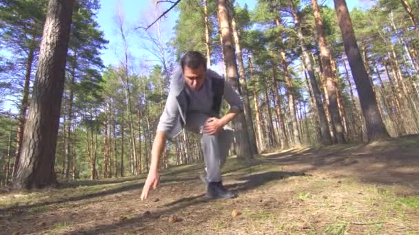 Людина під час бігу отримує травму коліна в сонячному лісі — стокове відео