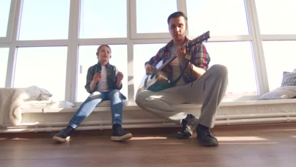 Padre e hija cantan una canción con una guitarra acústica — Vídeo de stock