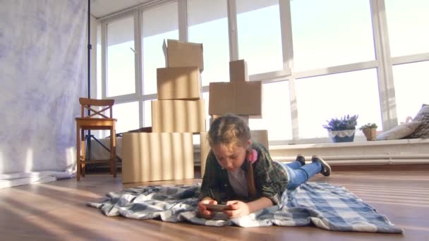 Niña 10-11 años de edad que utiliza un teléfono inteligente en el fondo de las cajas — Vídeo de stock