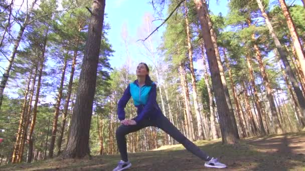 Sport meisje brunette die zich uitstrekt in een zonnig bos — Stockvideo