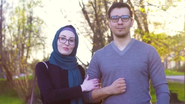Bonito jovem casal em óculos olha para a câmera no parque, ensolarado — Vídeo de Stock
