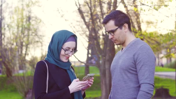 Chico y chica en hijab hablando en la calle en el parque — Vídeos de Stock