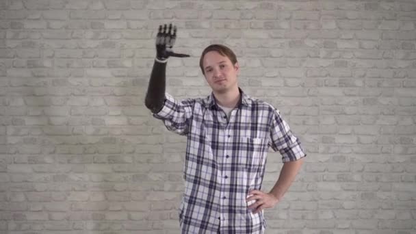 Positive young man waves a cyber prosthetic hand — Stock Video