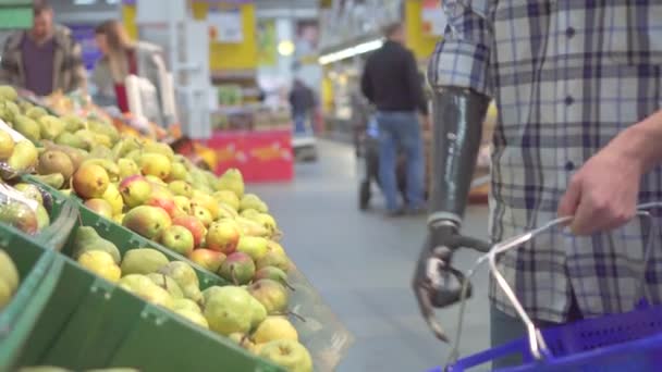 Young man with a bionic prosthetic arm in a supermarket shopping — ストック動画