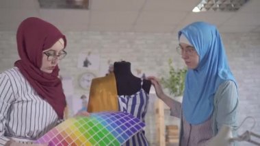 Genç Müslüman kadın moda tasarımcıları modern bir stüdyoda türban tasarlıyorlar.