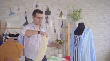 Genç adam moda tasarımcısı kumaşla çalışıyor.