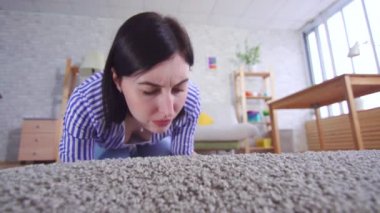 Oturma odasında genç bir kadın kötü kokan bir halıyı kokluyor.