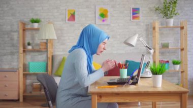 Ulusal başörtüsü takan genç Müslüman kadın dizüstü bilgisayarda çalışırken gözlerinde acı hissediyor