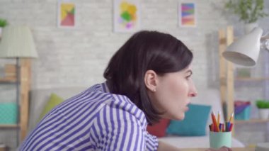 Dizüstü bilgisayarın başında oturan genç bir kadın boyun ve sırt ağrıları çekiyor.