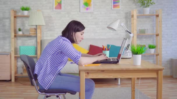 Young woman slouches sitting at a laptop — Stock Video