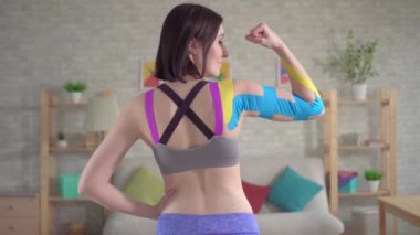 Güzel genç bayan sporcu renkli Kinesiotape pozu veriyor.