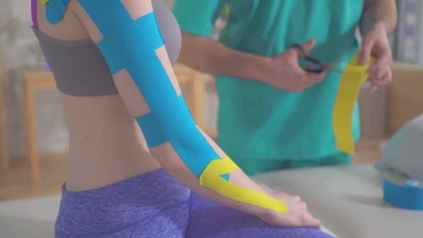 Sjukgymnast i uniform nedskärningar Kinesiotape med sax — Stockvideo