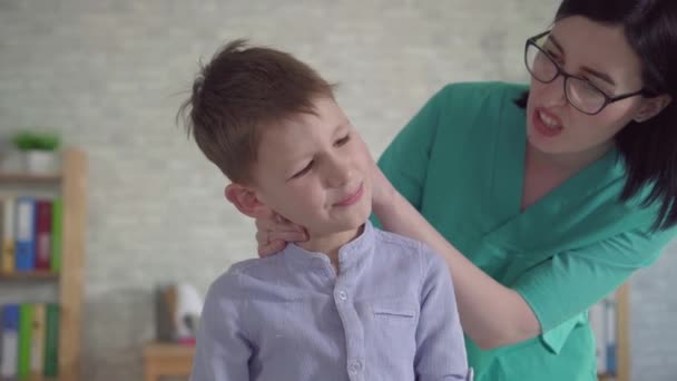 Fyzioterapeut zkoumá malé chlapce s bolavým krkem — Stock video