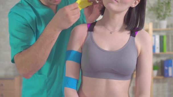 Fisioterapeuta con bastones uniformes Kinesiotape en el hombro de los pacientes — Vídeo de stock
