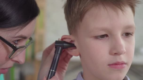 Толаринголог осматривает уши маленького мальчика вблизи — стоковое видео