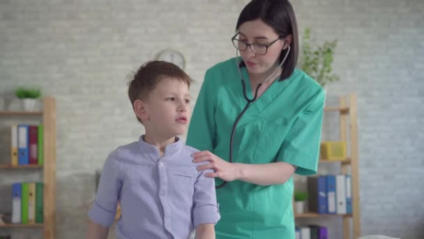 Kinderarts luistert met een stethoscoop naar een jongetje — Stockvideo