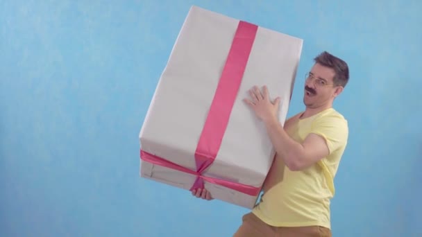 Vicces, boldog ember bajusszal, nagy, csomagolt ajándékkal. — Stock videók