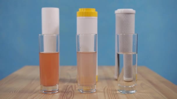 Идея концепции фильтры для воды и стаканы воды стоят на синем фоне — стоковое видео