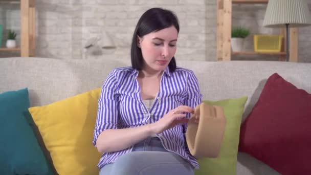 Young woman experiences neck pain and puts on a neck brace collar — Stock Footage Young woman experiences neck pain and puts on a neck brace collar Royalty Free Stock Footage