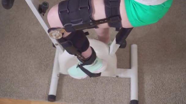 Нога на стационарном велосипеде колено согнуть ортез коленного корсета после травмы — стоковое видео