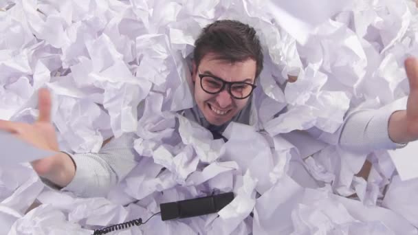 Hombre malicioso oficinista en gafas grita en un gran montón de papel arrugado lento mo — Vídeo de stock