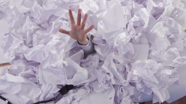 Man hand reikt uit een grote hopen verfrommeld papier — Stockvideo
