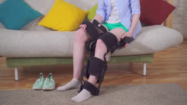 Young woman removes the orthosis from her leg after an injury and walks — 비디오