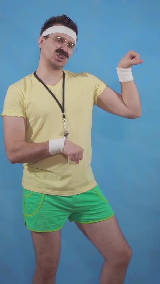 A funny trainer freak with a mustache in the style of the eighties shows off the muscles on a blue background — Stock Video