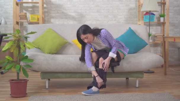 A portrait young woman takes orthosis from her leg after an injury and walks — Stock Video