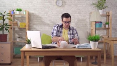 Genç bir baba, elinde akıllı telefon ve oyuncak bebek tutan bir çocuğu kundaklamayı öğrenir.