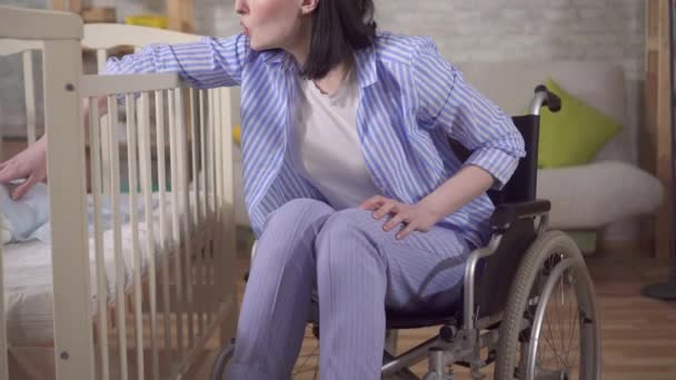 Jeune femme mère handicapée en fauteuil roulant dans la crèche gros plan — Video