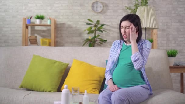 Усталая беременная женщина на диване будет испытывать дискомфорт и головную боль — стоковое видео