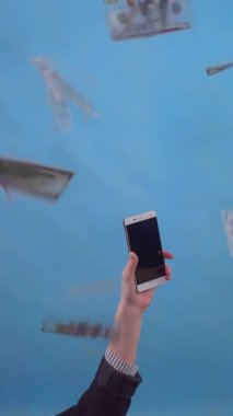 hand holding a smartphone against the background of falling banknotes isolate