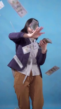 young business woman scatters throws paper money on a blue background of a vertical video slow mo