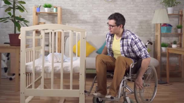 Disabile sulla sedia a rotelle un giovane padre in una camera da letto per bambini — Video Stock