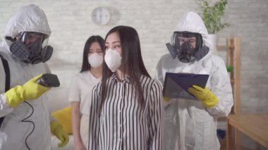 Doctors in protective overalls measure the temperature of Asian person
