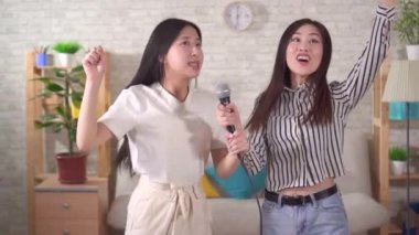 Two young asian woman sing karaoke at home slow mo