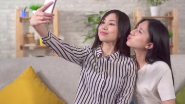 two happy young asian girls taking selfie close up