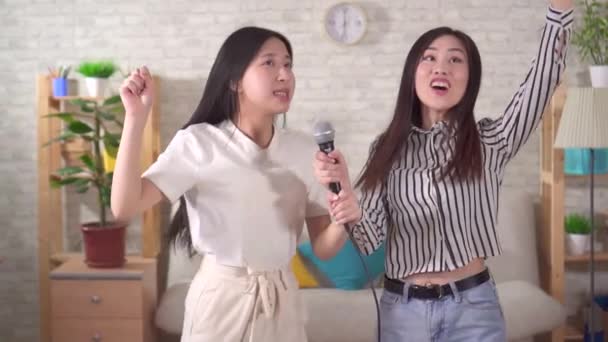 Two young asian woman sing karaoke at home slow mo — Wideo stockowe