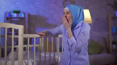 Yorgun bir portre. Genç bir kadın, bebek odasında yatağın yanında bir anne.