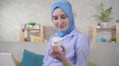 a Muslim young pregnant woman uses a laptop to search for information about the drug on the Internet